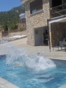 Τα κρυστάλλινα καθαρά νερά της πισίνας στον μεγάλο εξωτερικό χώρο της πέτρινης βίλας.
