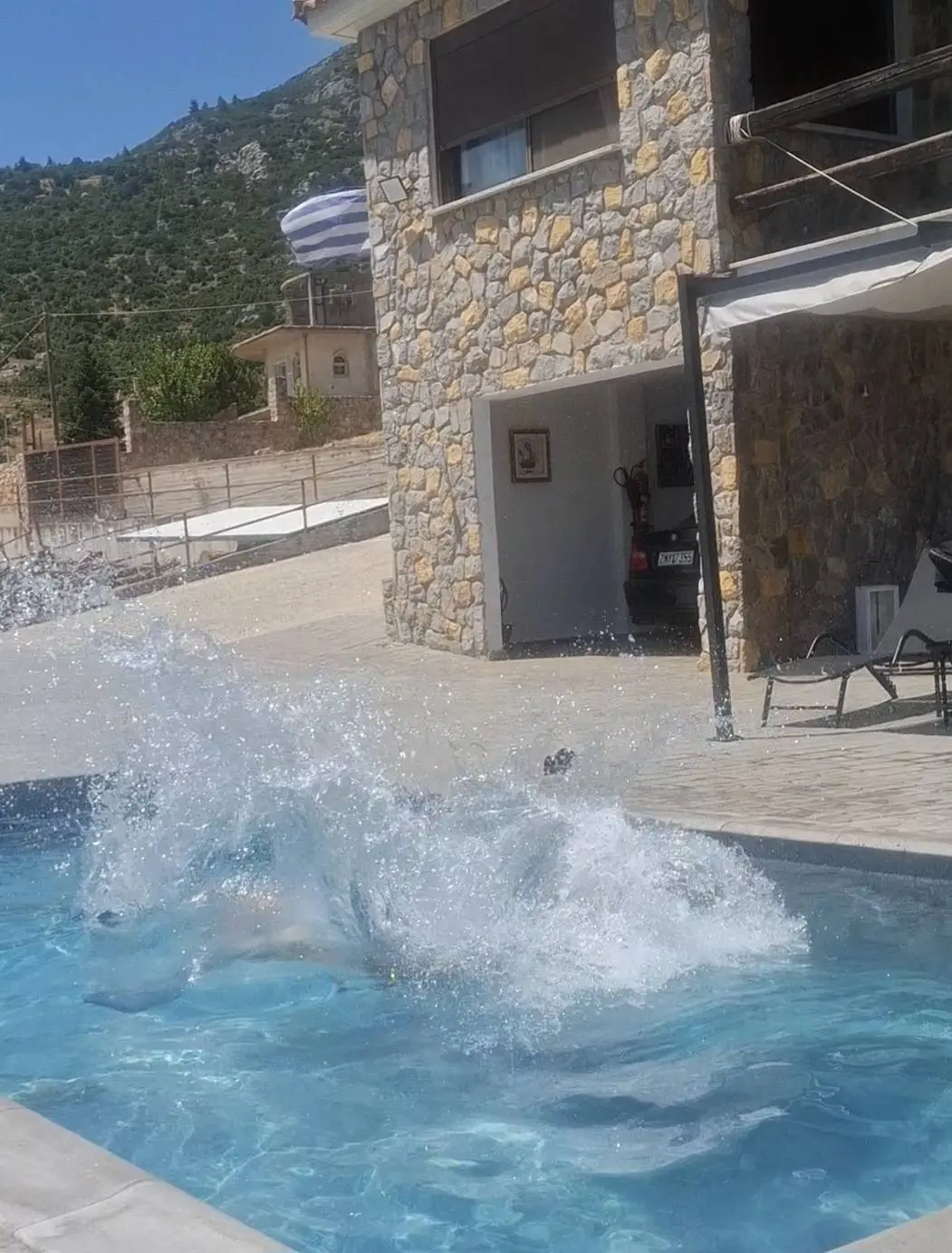 Τα κρυστάλλινα καθαρά νερά της πισίνας στον μεγάλο εξωτερικό χώρο της πέτρινης βίλας.