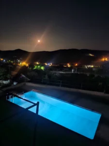 Βραδινή ατμόσφαιρα στη φωτισμένη ιδιωτική πισίνα της βίλας με θέα τον έναστρο ουρανό στα Βίλια.